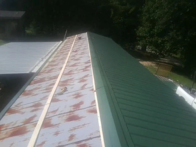 Old rusted panels beside newly installed green metal roofing — Wind Damage Roof Repair by Roofing Brothers in Otsego