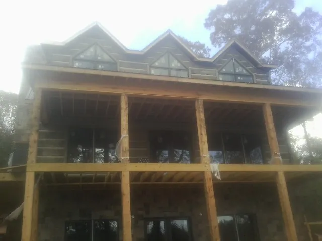 Dormers and porch framing on a large log home under construction — Roof Coating work by our crew in Otsego