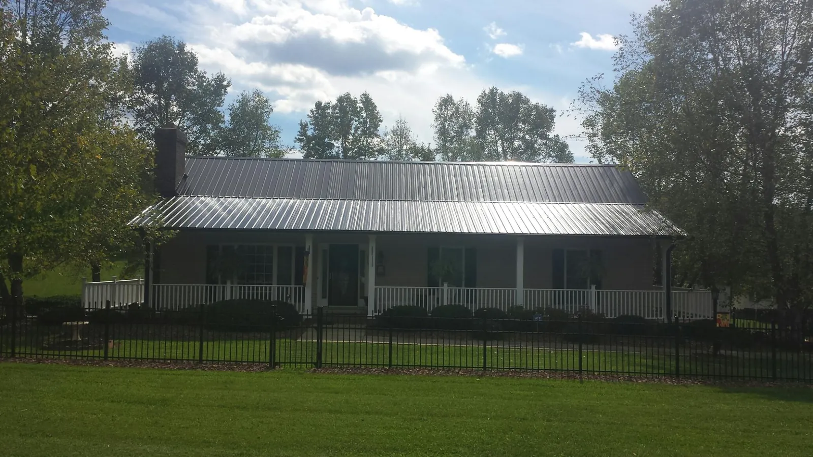 Gray metal roof on a brick ranch with a full width front porch — Gutter Guard Installation work by our crew in Otsego